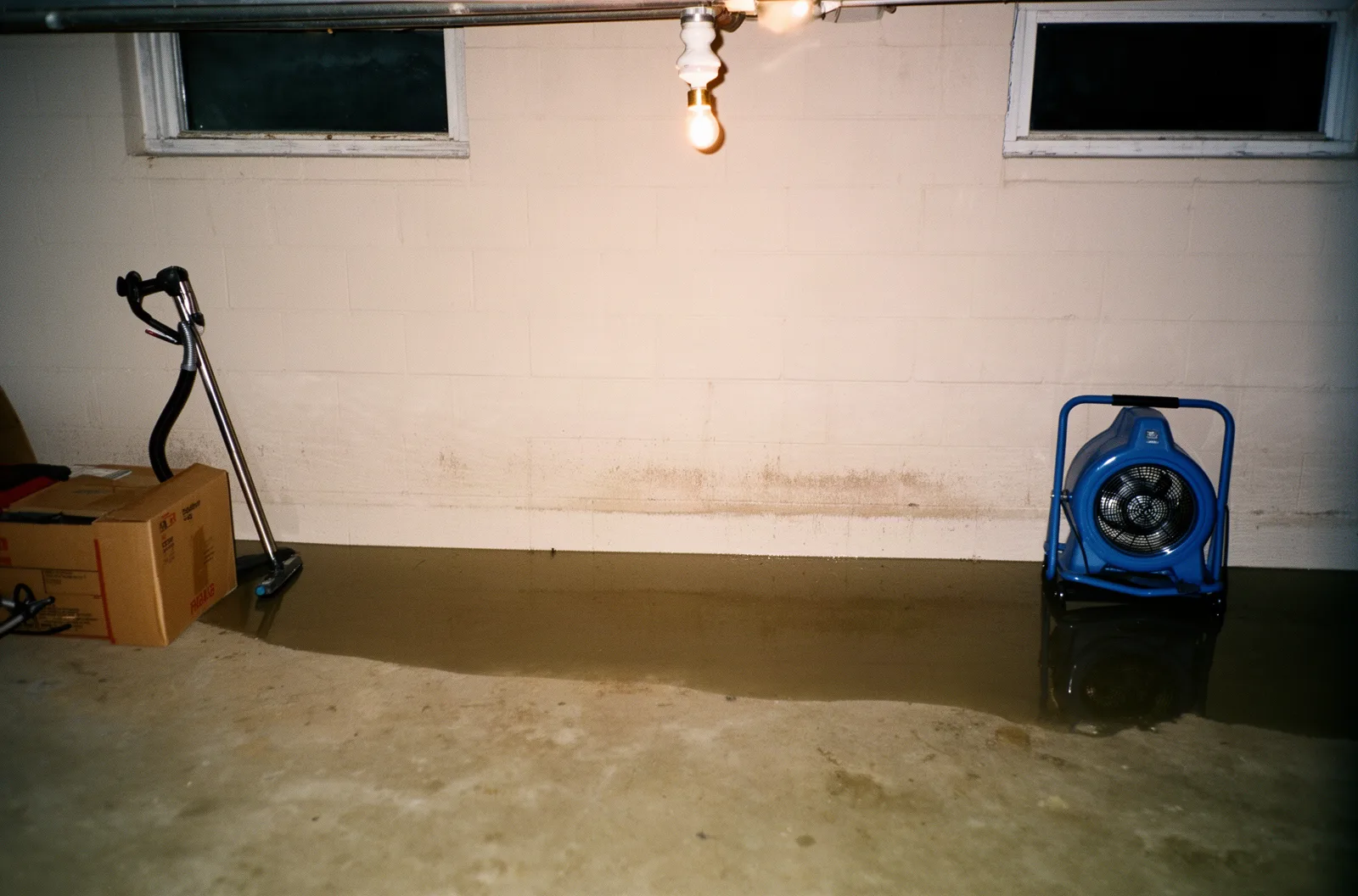 Standing water and drying equipment on a flooded basement floor